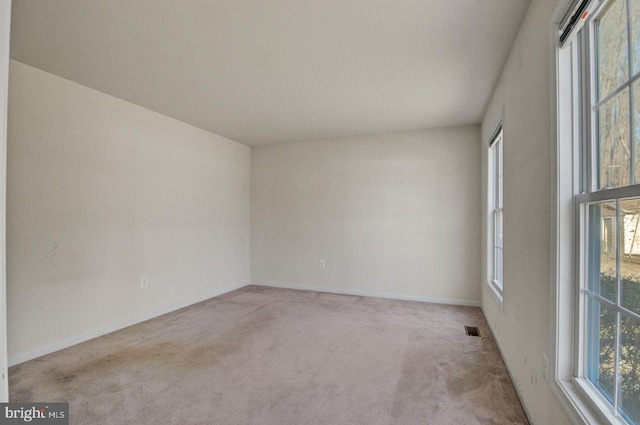 spare room with carpet flooring, plenty of natural light, visible vents, and baseboards