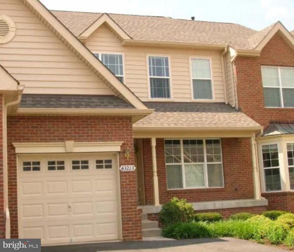 view of front of house featuring brick siding, driveway, an attached garage, and roof with shingles