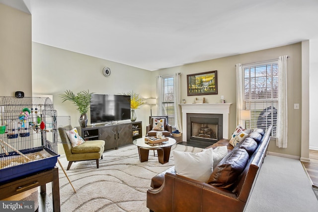 carpeted living room featuring a fireplace with flush hearth and baseboards