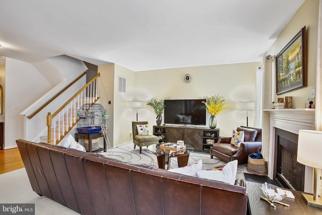 living room featuring stairs, a fireplace, and visible vents