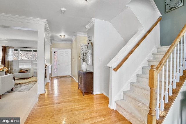 foyer with ornamental molding, stairway, light wood-type flooring, and baseboards