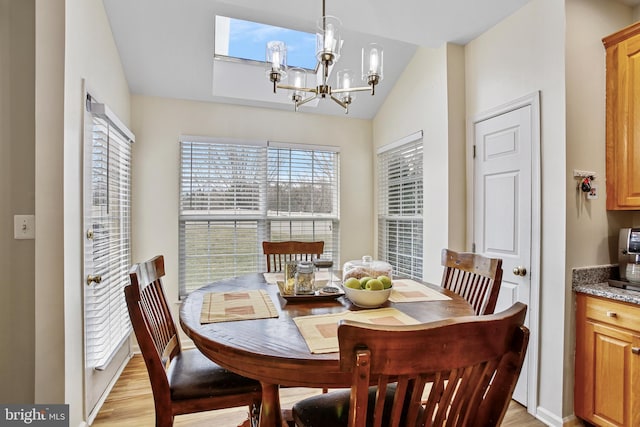 dining area with light wood-style floors, a chandelier, and vaulted ceiling