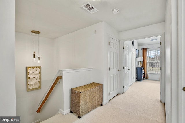 hallway with visible vents, carpet floors, and an upstairs landing