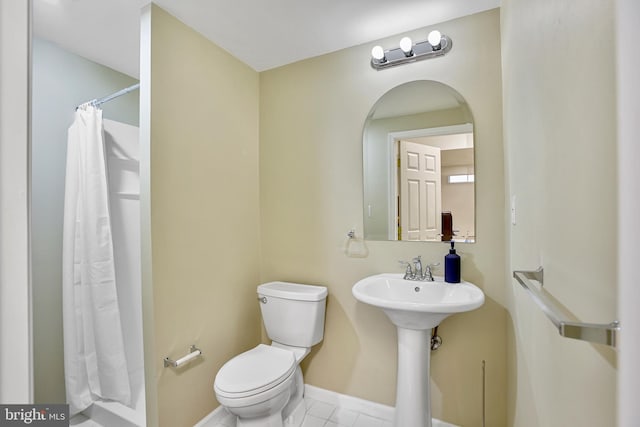 bathroom featuring curtained shower, tile patterned flooring, toilet, and baseboards