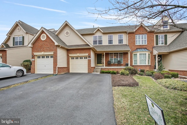 multi unit property with brick siding, a shingled roof, an attached garage, a front yard, and driveway