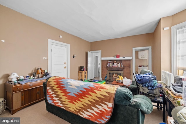 bedroom with light carpet, washer / clothes dryer, and a brick fireplace