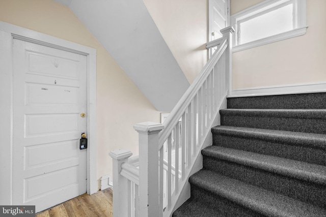 staircase featuring lofted ceiling and wood finished floors