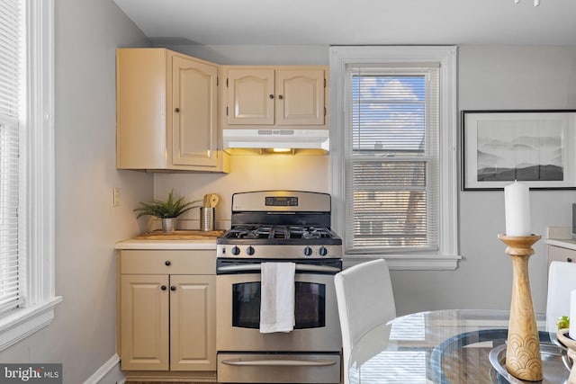 kitchen with under cabinet range hood, stainless steel range with gas cooktop, light countertops, and a wealth of natural light