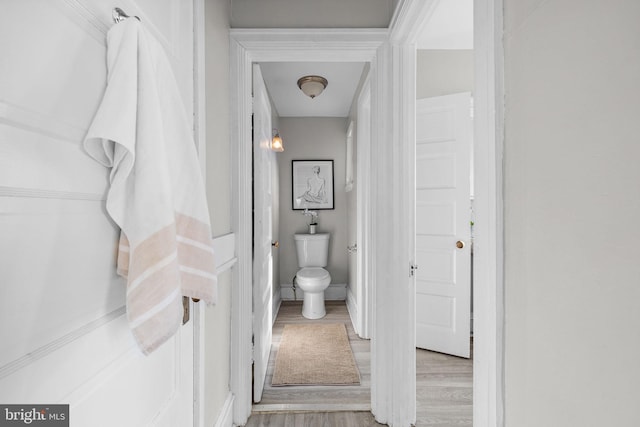 bathroom with toilet, baseboards, and wood finished floors