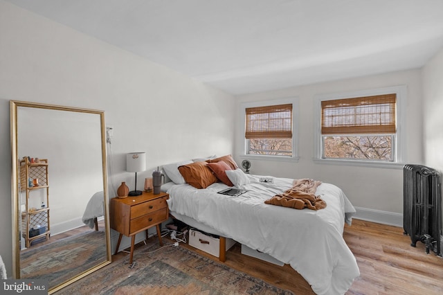 bedroom featuring baseboards, radiator heating unit, and wood finished floors