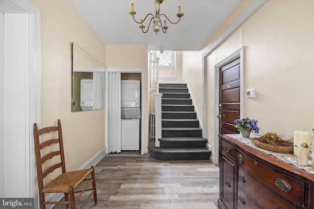 interior space with a chandelier, stacked washer and dryer, wood finished floors, and baseboards