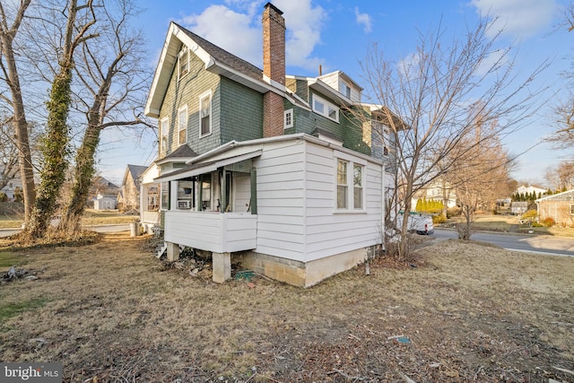 view of side of property with a shingled roof and a chimney