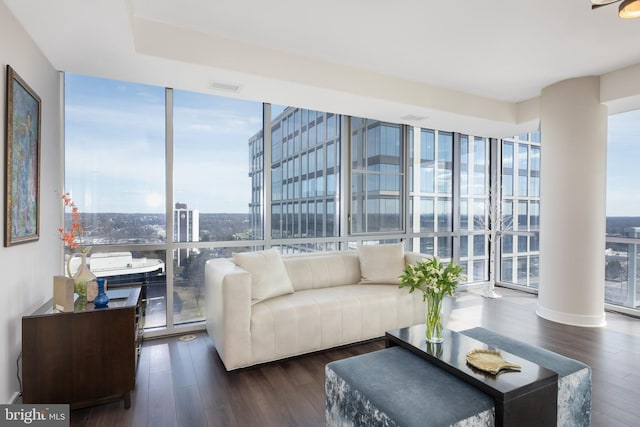 living area featuring expansive windows, visible vents, a city view, and wood finished floors