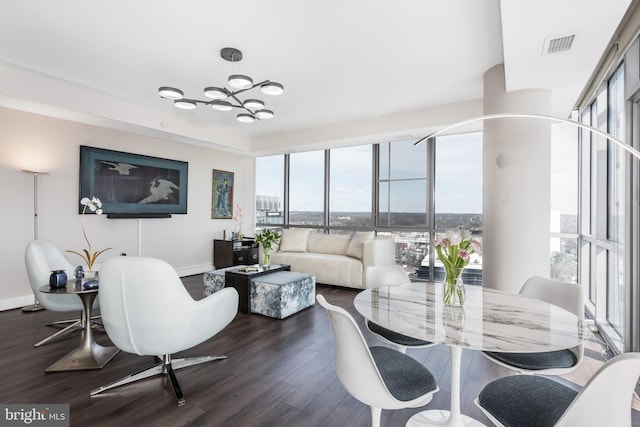 living area with dark wood finished floors, visible vents, an inviting chandelier, expansive windows, and baseboards