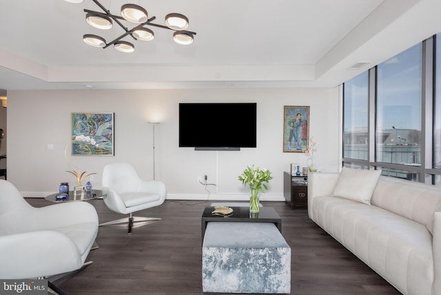 living area featuring a raised ceiling, visible vents, baseboards, and wood finished floors