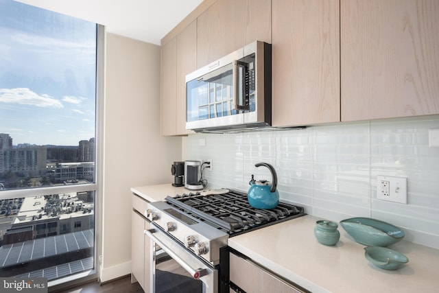 kitchen featuring stainless steel appliances, backsplash, modern cabinets, and light countertops