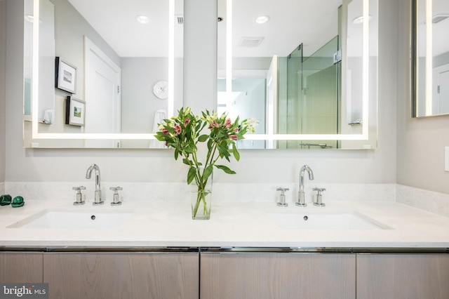 bathroom featuring double vanity, a sink, and recessed lighting