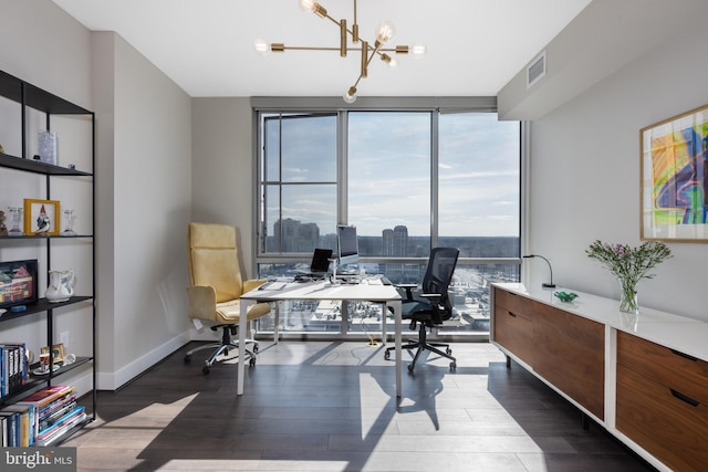 office area featuring wood finished floors, visible vents, baseboards, a wall of windows, and an inviting chandelier