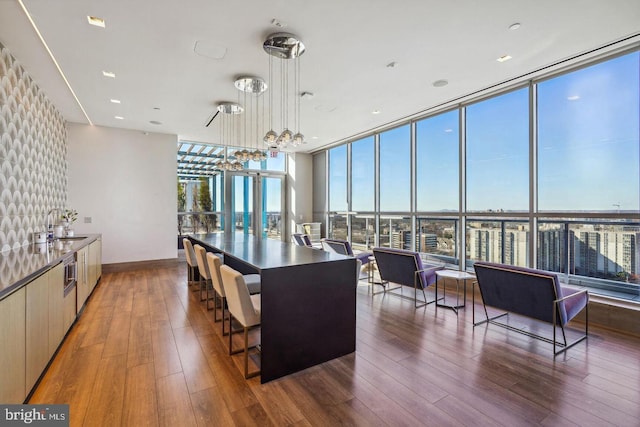 kitchen with decorative light fixtures, modern cabinets, wood finished floors, a wall of windows, and baseboards