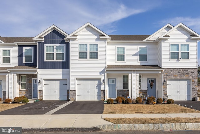 townhome / multi-family property featuring a garage, stone siding, driveway, and board and batten siding