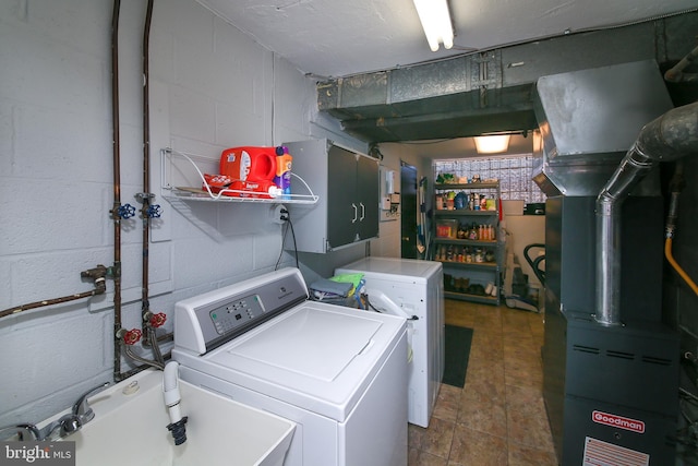 laundry room featuring concrete block wall, heating unit, a sink, and washing machine and clothes dryer