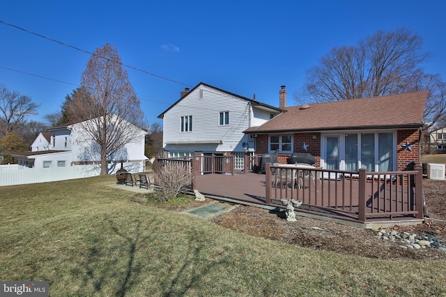 back of property with cooling unit, brick siding, fence, a lawn, and a wooden deck