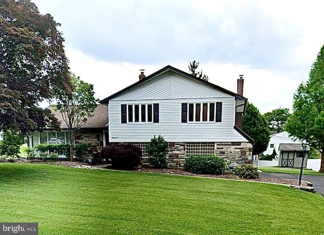 view of front of property with stone siding, a chimney, and a front lawn