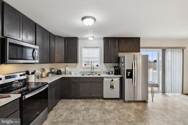 kitchen with dark brown cabinets, appliances with stainless steel finishes, light countertops, and a sink