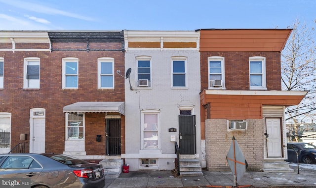 view of property with entry steps, brick siding, and a wall mounted AC