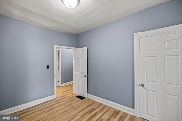 empty room featuring light wood finished floors, visible vents, and baseboards