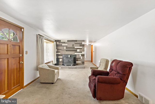 living room with visible vents, baseboards, a wood stove, and carpet