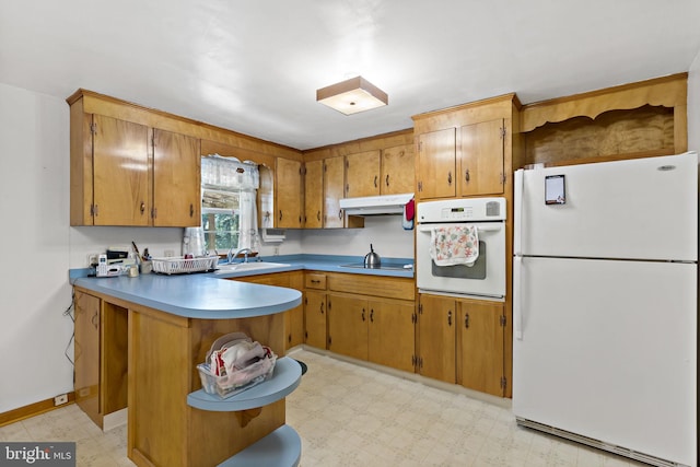 kitchen featuring white appliances, brown cabinetry, light floors, and under cabinet range hood