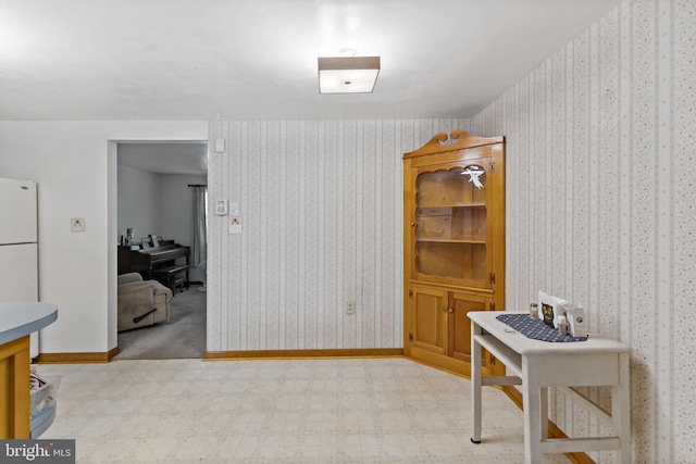 interior space featuring wallpapered walls, tile patterned floors, and baseboards