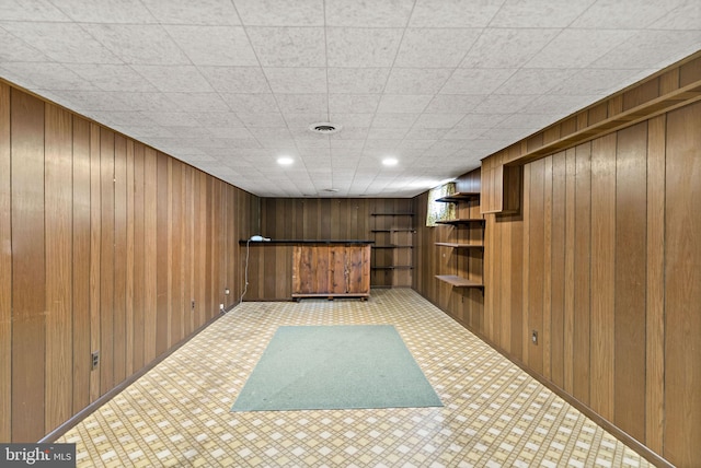 finished basement featuring wooden walls, visible vents, and light carpet