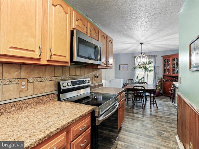 kitchen featuring decorative light fixtures, backsplash, appliances with stainless steel finishes, a textured ceiling, and wood finished floors