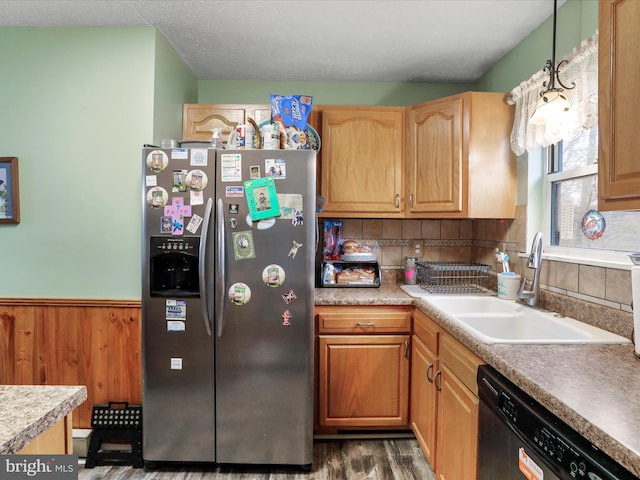 kitchen with a wainscoted wall, light countertops, a sink, stainless steel fridge, and dishwashing machine