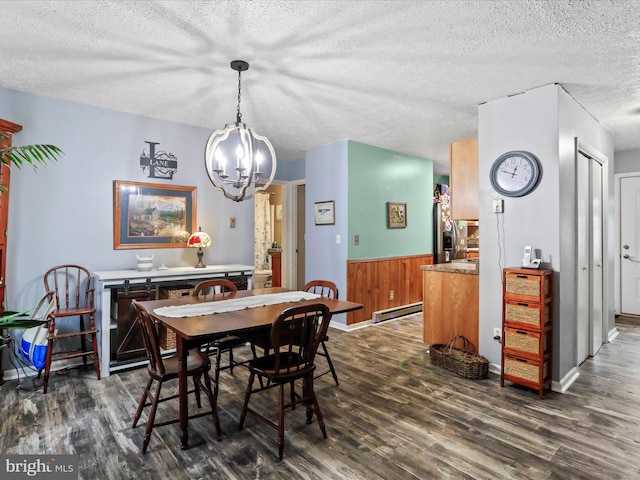 dining space featuring dark wood-style floors, a textured ceiling, a baseboard radiator, and a wainscoted wall