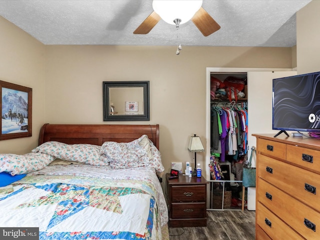 bedroom with a textured ceiling, ceiling fan, dark wood-style flooring, a spacious closet, and a closet