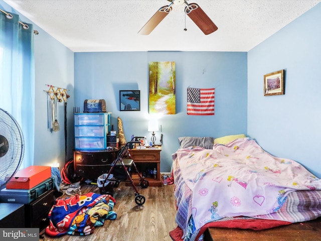 bedroom with ceiling fan, a textured ceiling, and wood finished floors