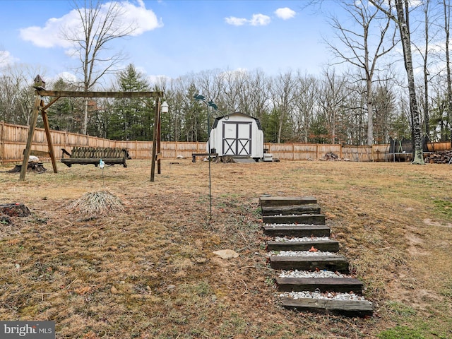 view of yard featuring a shed, a fenced backyard, and an outbuilding