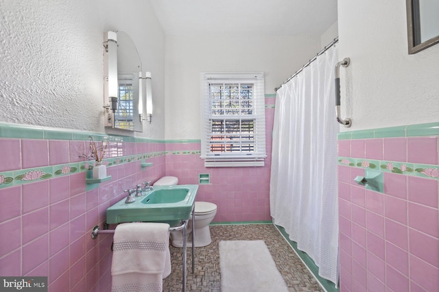 7310 Alaska Ave NW, Washington, DC 20012 - full bathroom with a wainscoted wall, tile walls, toilet, a sink, and a shower with curtain