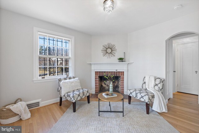 7310 Alaska Ave NW, Washington, DC 20012 - sitting room with arched walkways, visible vents, baseboards, light wood-style floors, and a brick fireplace