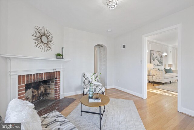 7310 Alaska Ave NW, Washington, DC 20012 - living area featuring visible vents, arched walkways, baseboards, wood finished floors, and a brick fireplace