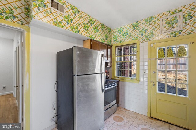 7310 Alaska Ave NW, Washington, DC 20012 - kitchen with light tile patterned floors, stainless steel appliances, tile walls, visible vents, and wallpapered walls