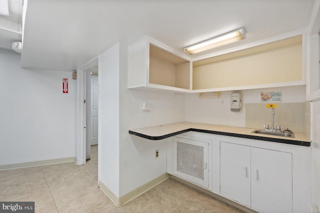 7310 Alaska Ave NW, Washington, DC 20012 - kitchen with light tile patterned floors, open shelves, white cabinetry, a sink, and baseboards