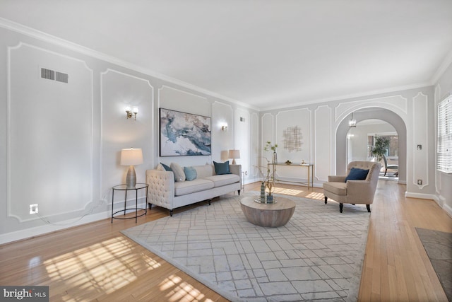 7310 Alaska Ave NW, Washington, DC 20012 - living room featuring baseboards, visible vents, arched walkways, crown molding, and light wood-type flooring