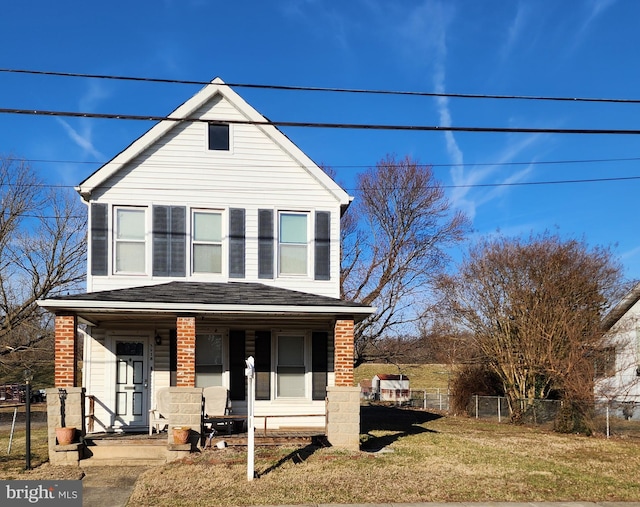 view of front of property with brick siding, roof with shingles, a porch, a front yard, and fence