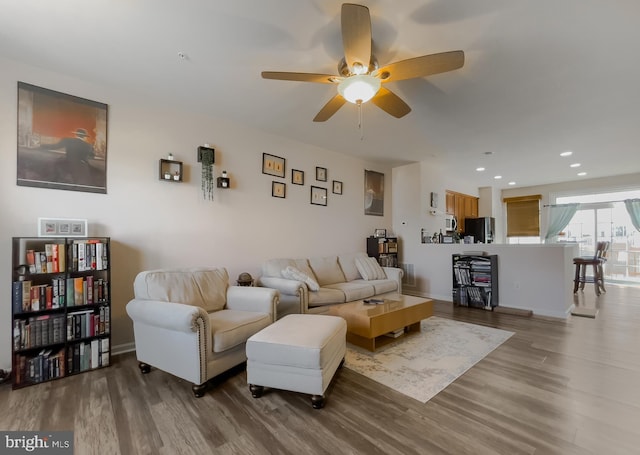 living area featuring baseboards, ceiling fan, wood finished floors, and recessed lighting