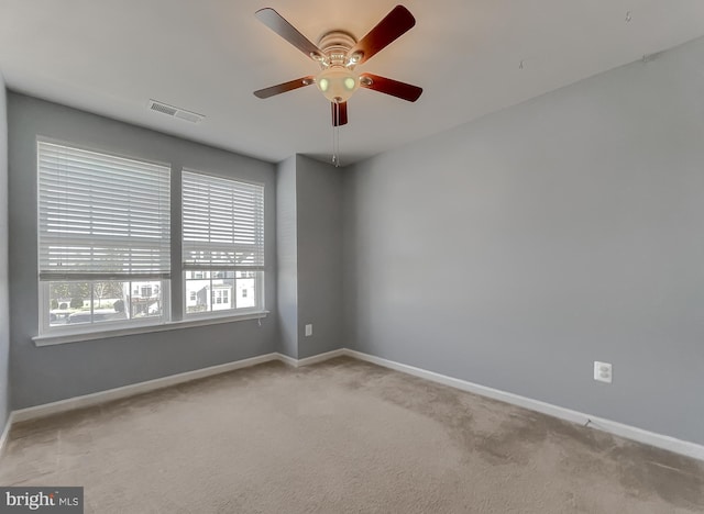 spare room with light carpet, baseboards, visible vents, and ceiling fan