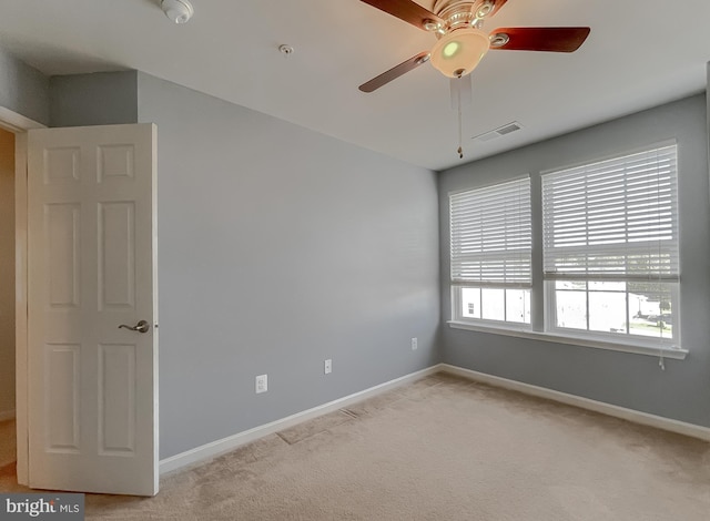 unfurnished room featuring baseboards, a ceiling fan, visible vents, and light colored carpet